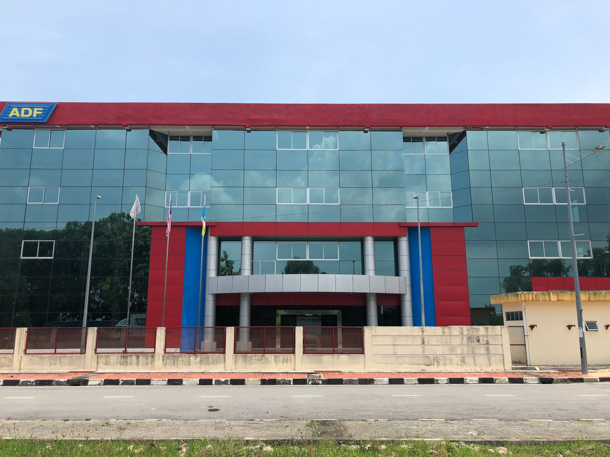 Modern building in Malaysia with glass facade and red and blue accents.